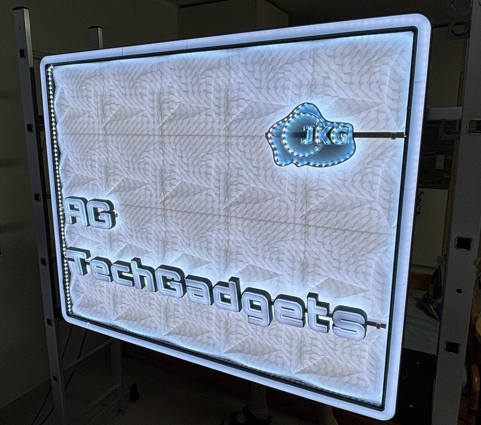 Beleuchtetes LED-Wandschild mit Schriftzug AG TechGadgets und JKG-Logo